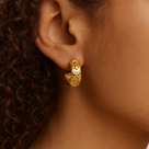 Close-up of a person wearing a gold hoop earring with celestial design.
