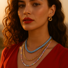 Woman wearing a red top and multiple necklaces with a blurred background dorsya