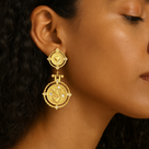 Close-up of a woman wearing a gold earring with intricate design